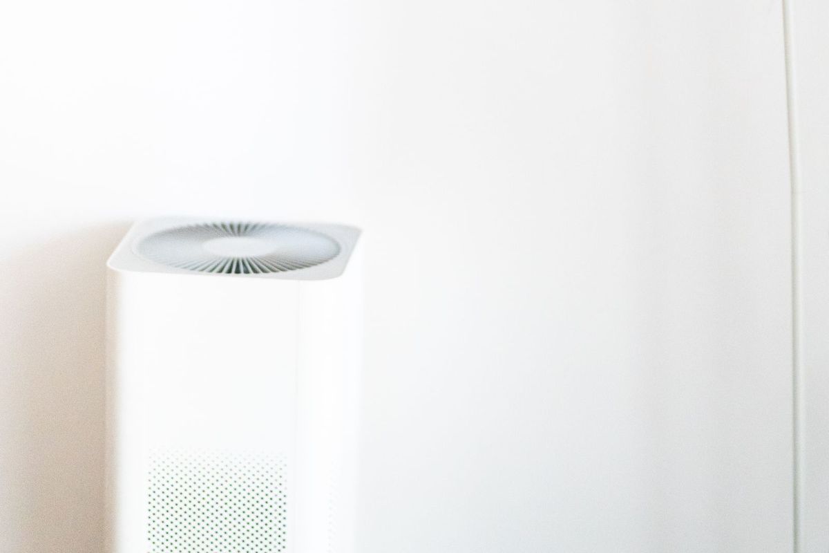 White air purifier standing against a white wall