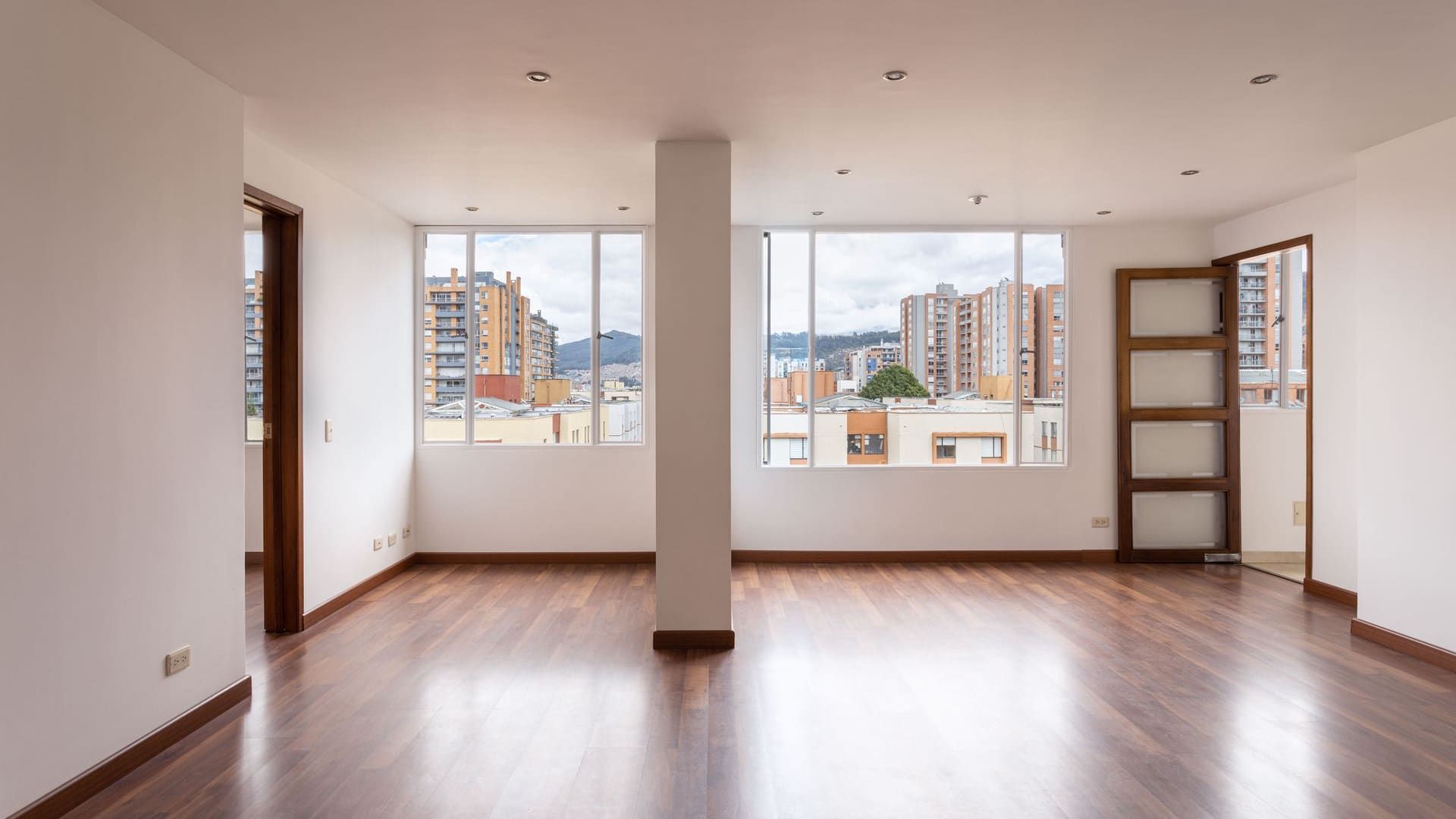 Empty apartment with wood floors and windows overlooking the city