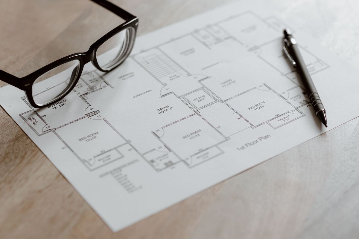 Apartment floor plan with several bedrooms, a pen and glasses on a table