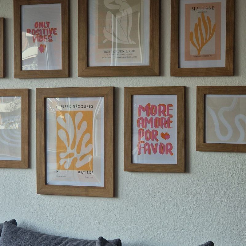 Gallery wall of framed art prints above a gray sofa with throw pillows