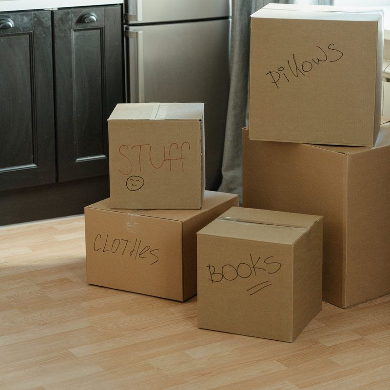 Moving boxes labeled stuff, clothes, books and pillows in a kitchen