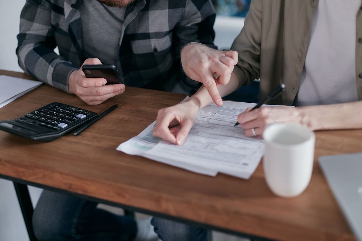 Two people at a table going over a bill with a calculator and a phone