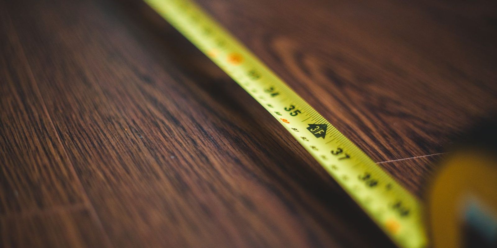 Yellow tape measure stretched across a wood floor