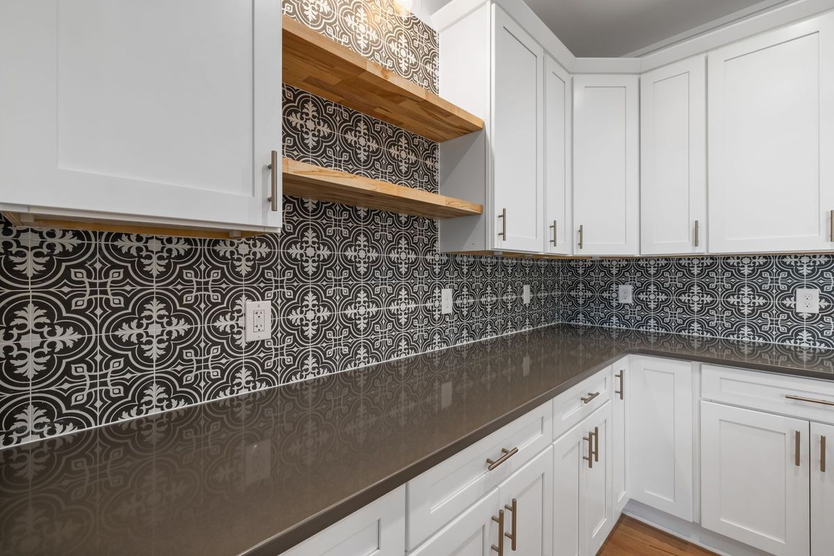 Black and white patterned tile backsplash behind white kitchen cabinets