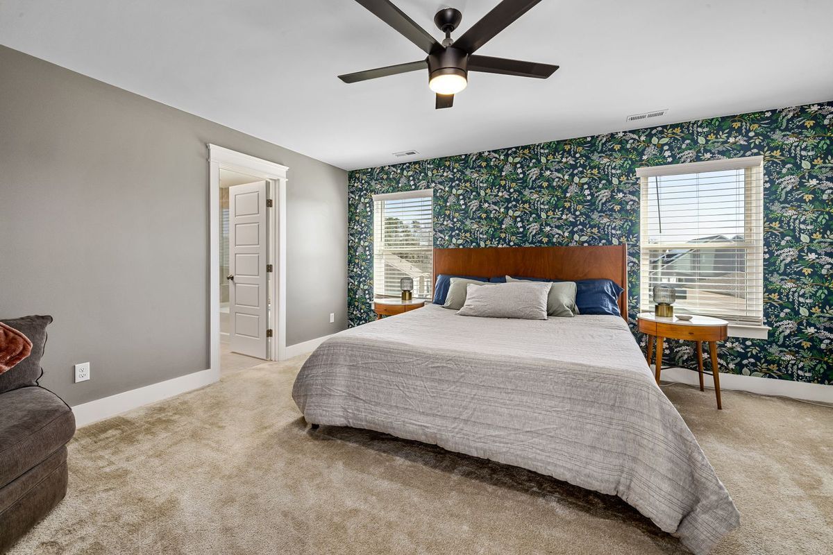 Bedroom with a dark green leaf-pattern wallpaper accent wall behind the bed